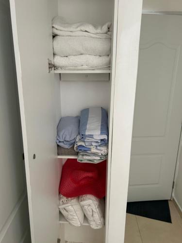 ein weißer Kleiderschrank mit Handtüchern und Kleidung darin in der Unterkunft La marquesa in Los Paredones