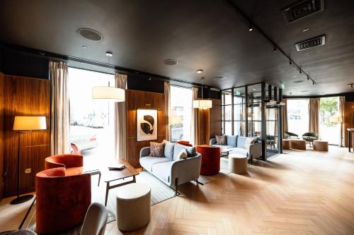 a living room with couches and chairs and windows at Wilde Aparthotels London Aldgate Tower Bridge in London