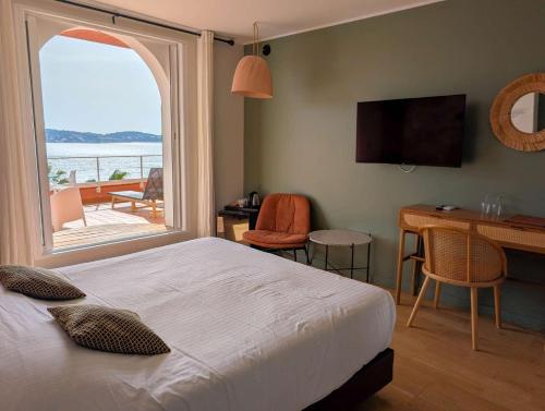 a bedroom with a bed and a desk and a window at Les Galets Hôtel et B&B in Bandol