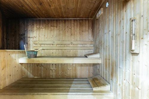 a sauna with a wooden wall and a bucket on a shelf at BHost - Bellagio II in Benalmádena