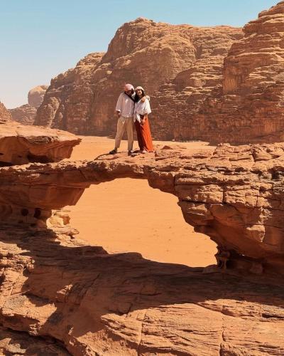 deux personnes debout sur un rocher dans le désert dans l'établissement Desert Time, à Wadi Rum