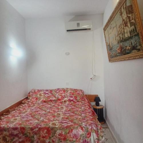 a bedroom with a bed with a floral bedspread at Bungalow kantaoui Sousse in Hammam Sousse