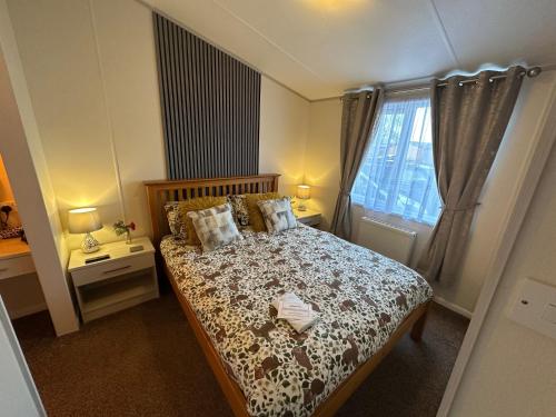 a bedroom with a bed with pillows and a window at Indulgence Lakeside Lodge i2 with hot tub, private fishing peg situated at Tattershall Lakes Country Park in Tattershall
