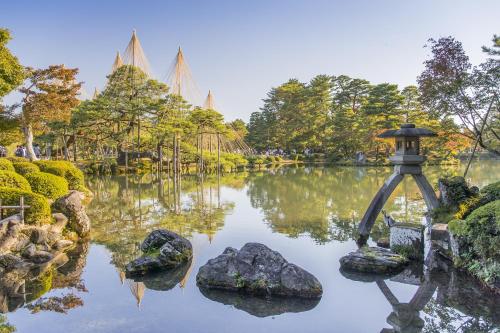 a garden with a pond with rocks and trees at Kanazawa Station Hotel in Kanazawa