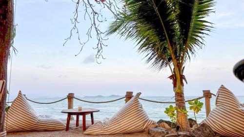 a beach with chairs and a table and a palm tree at Klang Aow Resort in Khanom
