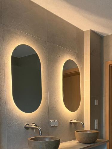 two sinks in a bathroom with two mirrors at Urlaub-Im-Erletal in Schleusingen