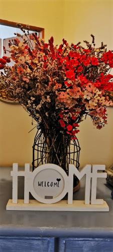 a sign with a bunch of red flowers in a basket at Casa da Avó Isaura - Ericeira in Ericeira