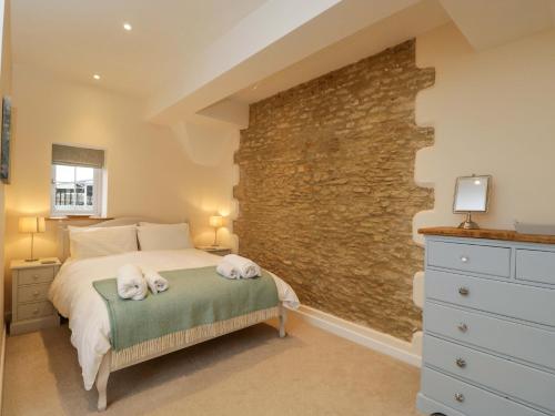 a bedroom with a bed and a stone wall at Stanbridge Cottage in Malmesbury