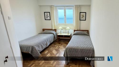two beds in a room with a window at Torres de Manantiales Apart Hotel in Mar del Plata