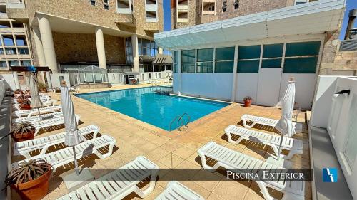 a swimming pool with lounge chairs in a building at Torres de Manantiales Apart Hotel in Mar del Plata