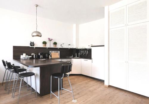 a kitchen with a black counter and stools at DUENENROSE App Nr 03 max 3 Pers in Dierhagen