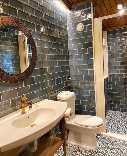 a bathroom with a sink and a toilet and a mirror at Laklouk Village Vacances in Jbeil