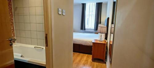 a bathroom with a bed and a tub in a room at Grand Plaza Serviced Apartments in London