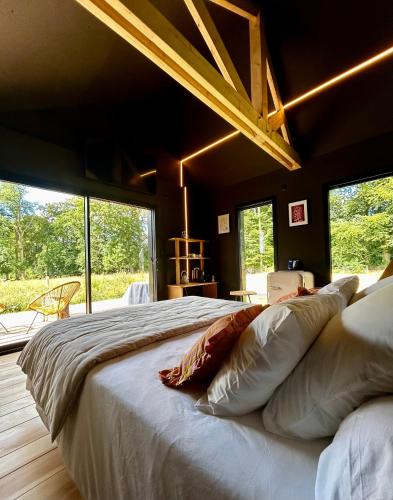 a large bed in a room with large windows at Le Vert d'Orezza in Valliquerville