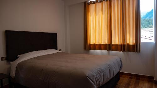 a bedroom with a bed and a window with curtains at Depa Urubamba in Urubamba