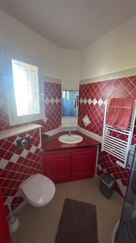 a red bathroom with a toilet and a sink at Villa Bella Vita in Biguglia