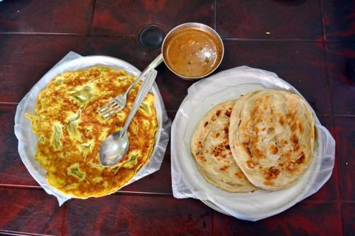 a table with two plates of food with a fork and pancakes at The Aristocrat Residency in Islamabad