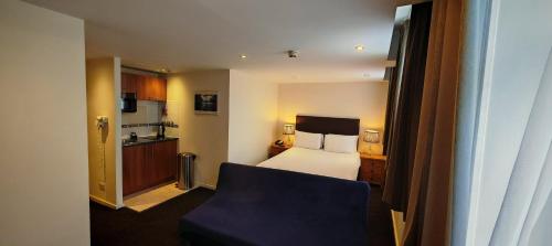 a hotel room with a bed and a chair at Grand Plaza Serviced Apartments in London