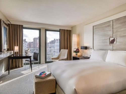 a hotel room with a large bed and a desk at Sofitel Brussels Europe in Brussels