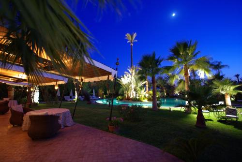 a resort with a pool and palm trees at night at Lodge K in Marrakech