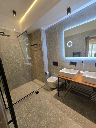 a bathroom with two sinks and a toilet and a mirror at Hotel Nefeli in Volos