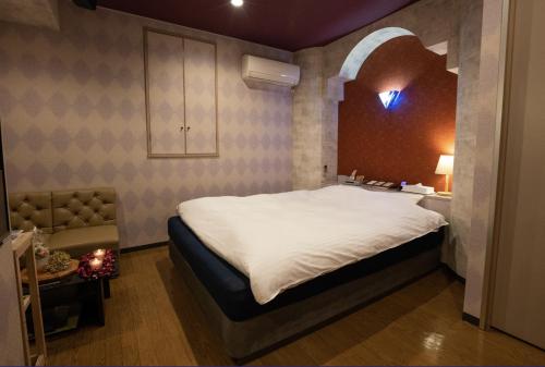 a bedroom with a large bed and a chair at ホテルパルシス大人専用 in Shiroishi