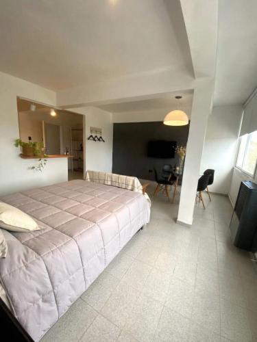 a bedroom with a large bed and a living room at NuMa MAR in Puerto Madryn