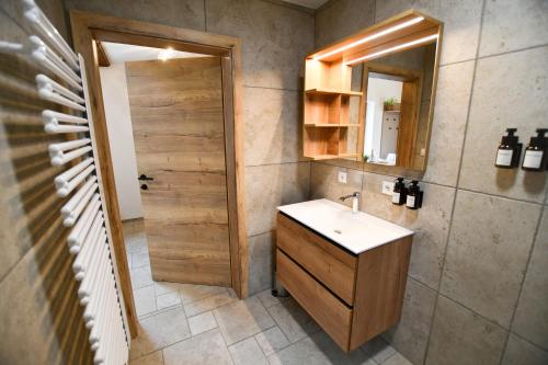 a bathroom with a sink and a mirror and a door at Wohlfühl Apartments am Hof Rapotz in Leutschach