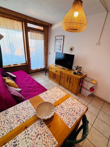 a living room with a table and a tv at Edelweiss Pila-Ski appartment con vista montagne in Pila