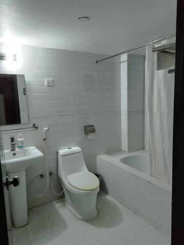 a bathroom with a toilet and a tub and a sink at Hotel Crown in Rājshāhi