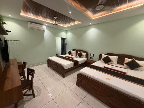 a hotel room with two beds and a television at Nirmala Grand in Rāmeswaram