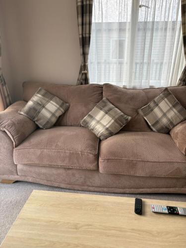 a brown couch with pillows in a living room at Home from Home at the Hendersons Caravan in Kilwinning