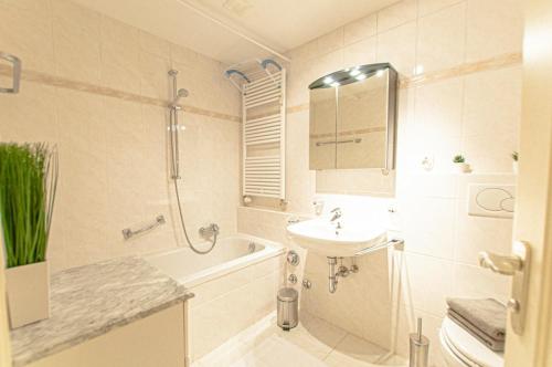 a bathroom with a sink and a toilet and a bath tub at Ferienwohnung Steinfeldstrasse am Tegernsee in Rottach-Egern