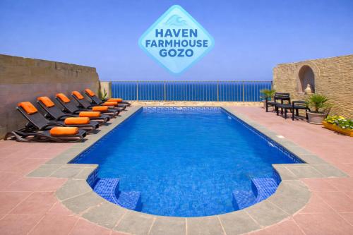 a swimming pool with chairs next to a building at Haven Farmhouse with Private Pool and Sea Views in Għajn Melel