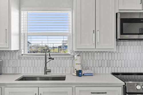 a kitchen with white cabinets and a sink and a window at Chulavista Cozy Close to beach in Galveston