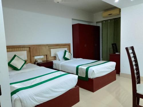 a hotel room with two beds in a room at Hotel Crown in Rājshāhi