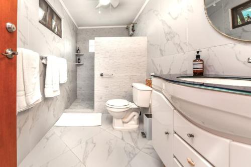 a white bathroom with a toilet and a sink at Beachfront Two-Bedroom Villa in Savaneta