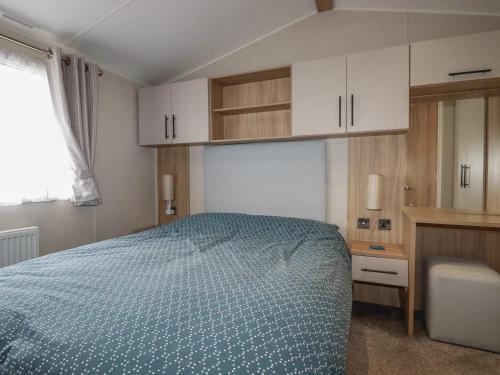 a bedroom with a bed and white cabinets and a window at Eth Melyn Caravan Holiday in Grampound