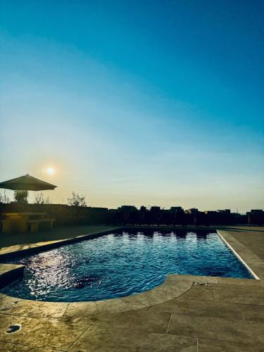 a swimming pool with the sun setting in the background at Pitt House in Nadur