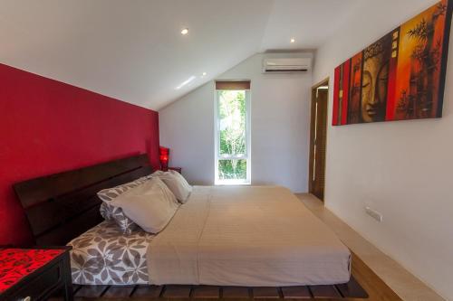 a bedroom with a large bed with a red wall at Malee Beach F3 in Phra Ae beach
