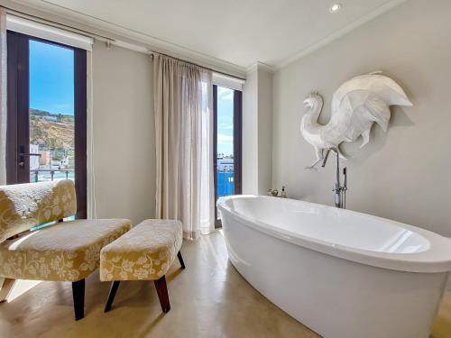 a bathroom with a large white tub and a bird on the wall at Rouge on Rose Boutique Hotel in Cape Town