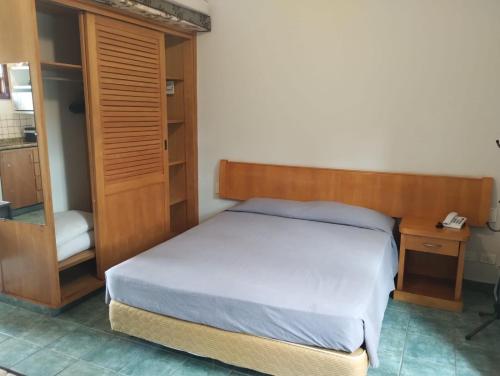 a bedroom with a bed with a wooden headboard and a desk at Beira mar Flat 2-209 in Ilhabela