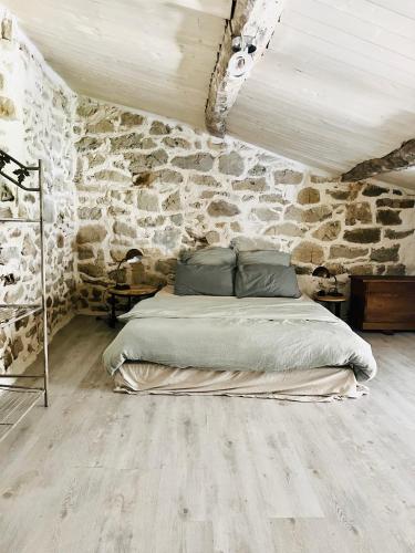 a bedroom with a bed in a stone wall at Aube du Tilleul in Lagorce