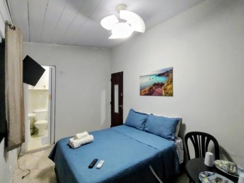 a bedroom with a blue bed and a bathroom at Solares Aconchego - Suíte in Búzios