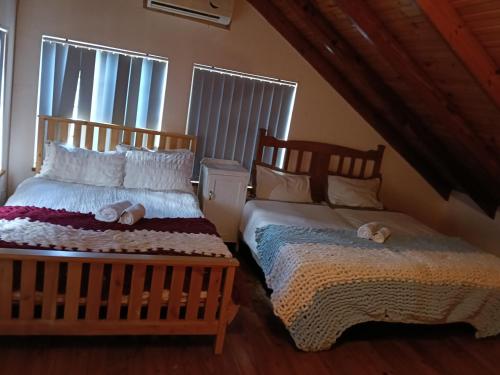 a bedroom with two beds and two windows at The Victorian Villa in Chintsa
