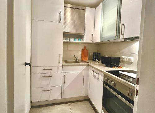 a white kitchen with white cabinets and a sink at Ferienwohnung Steinbock mit Bergblick in Bayrischzell