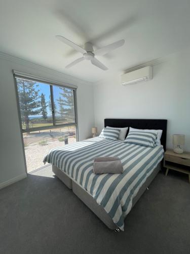 a bedroom with a striped bed with a ceiling fan at Coastal Calm Seascapes Halls Head in Falcon