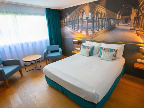 a bedroom with a large bed with blue curtains at Mercure Mont Saint Michel in Le Mont Saint Michel