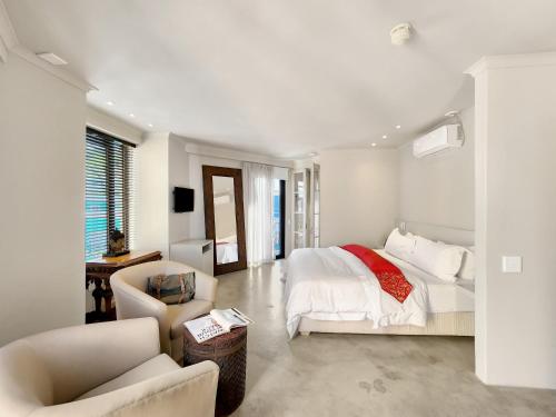 a white bedroom with a bed and a chair at Rouge on Rose Boutique Hotel in Cape Town