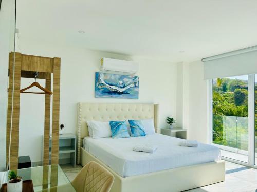 a white bedroom with a bed with blue pillows at The Views Resort in El Zonte